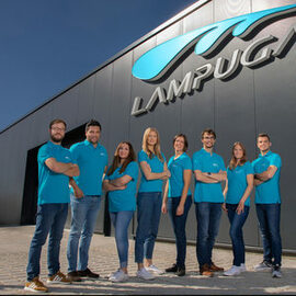 Das Lampuga-Team steht mit blauen Poloshirts vor der Produktionshalle